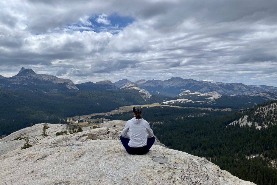 a hiker sitting on top of a viewpoint and watching a 360 panorama with mountains in the distance, Yosemite national park